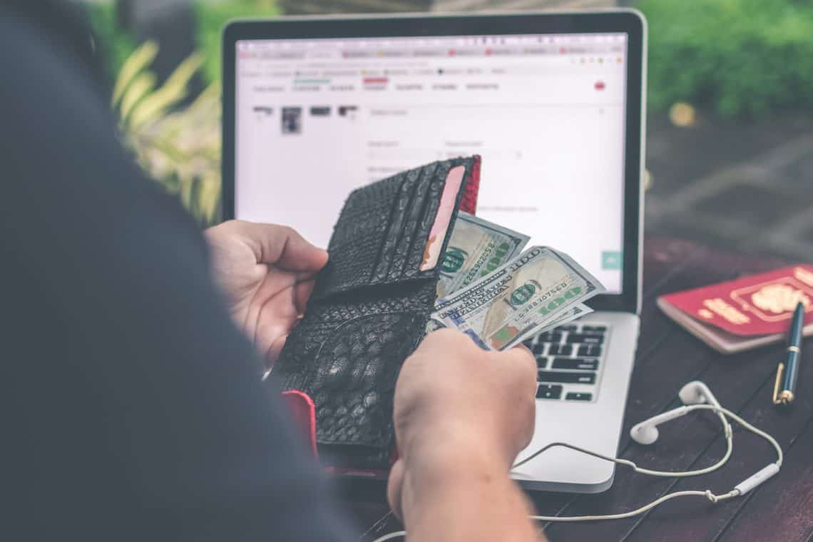 Person opening wallet in front of computer